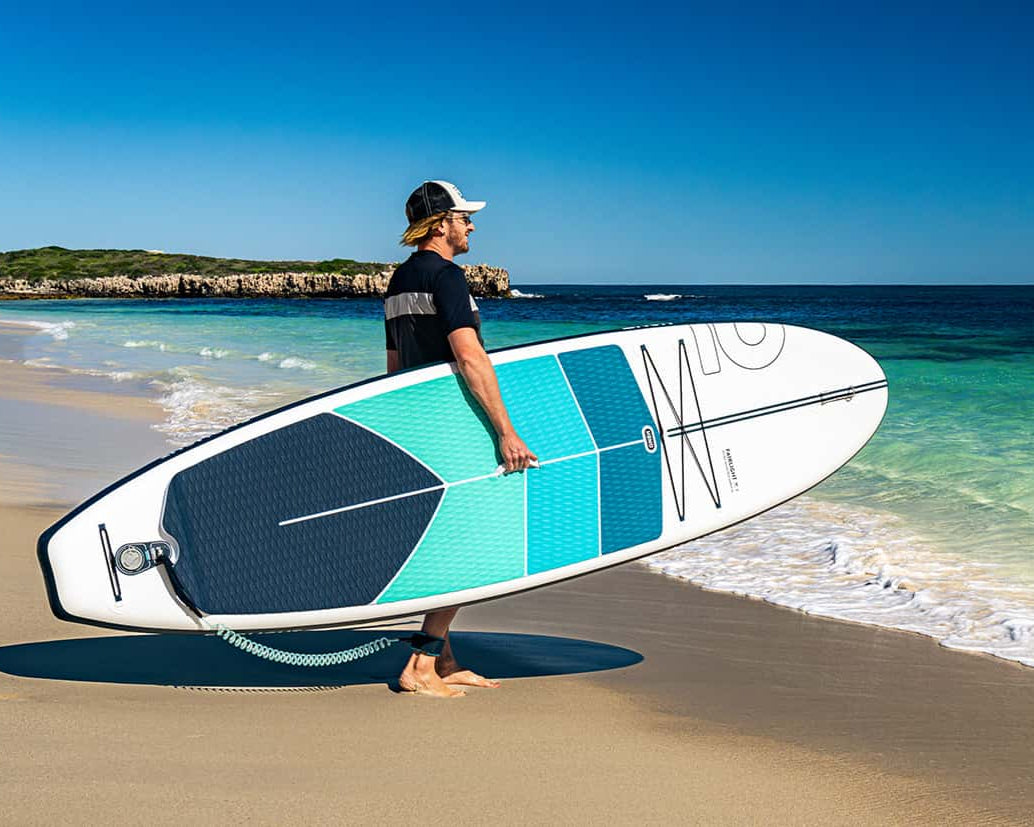 Honu Fairlight 10' 9" All-rounder sea turtle 2024 carried to the water by its paddleboard owner