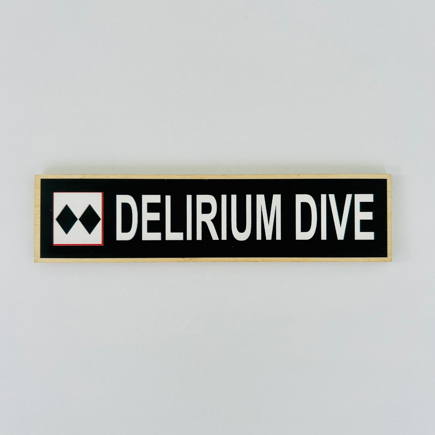 Rectangular sign with 'DELIRIUM DIVE' text on a light gray background