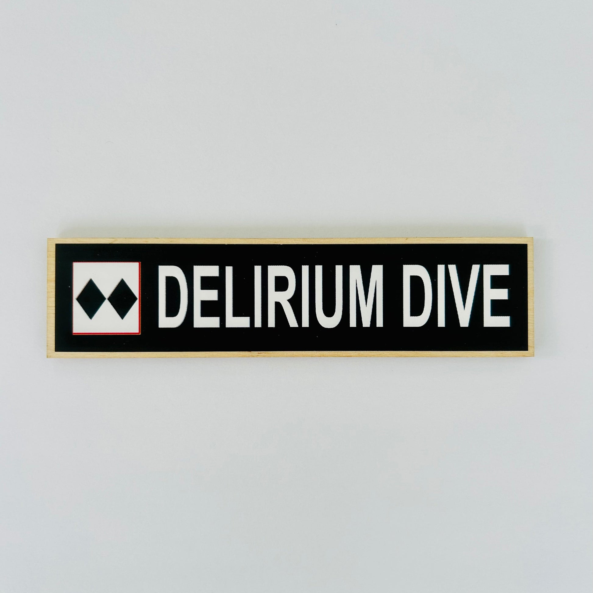 Rectangular sign with 'DELIRIUM DIVE' text on a light gray background