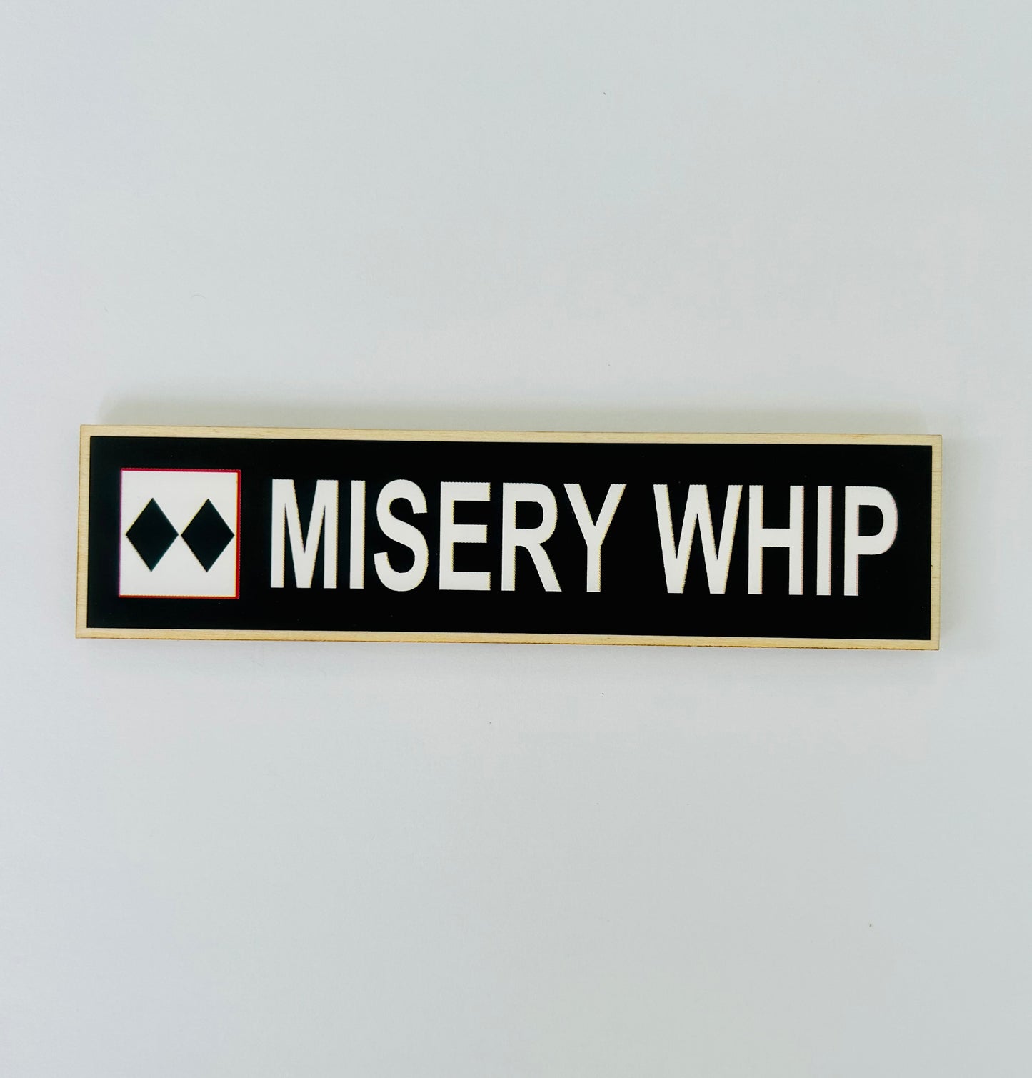 Rectangular sign with 'MISERY WHIP' text on a white background