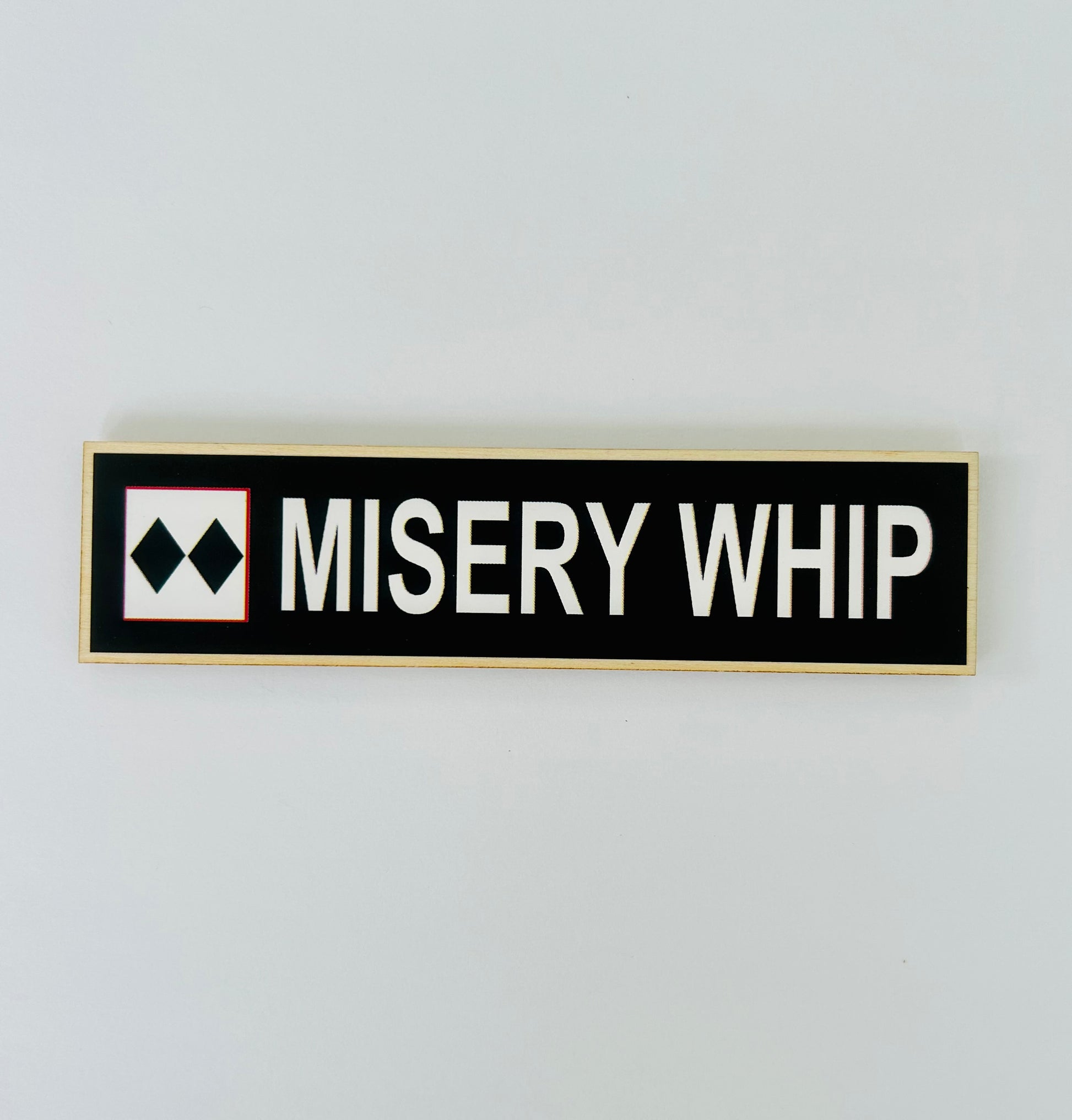 Rectangular sign with 'MISERY WHIP' text on a white background