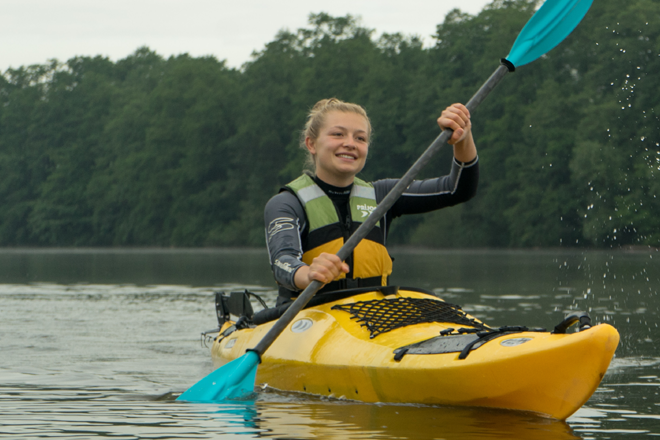 Person kayaking on a lake with trees in the background