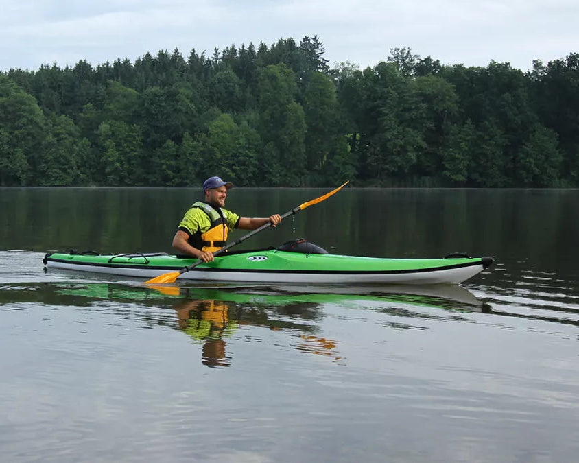 Person kayaking on a calm lake with trees in the background