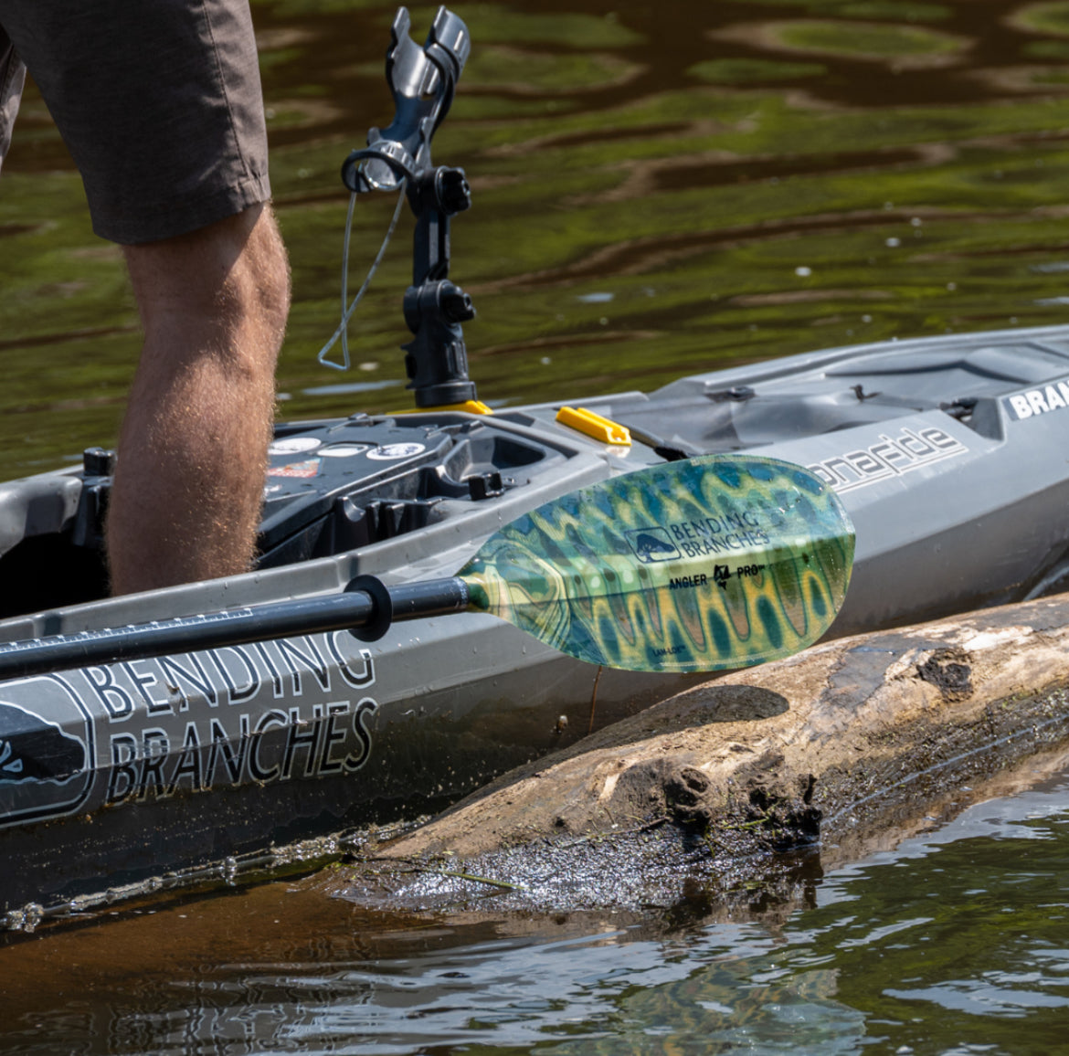 Person in a kayak with a paddle, on a body of water.
