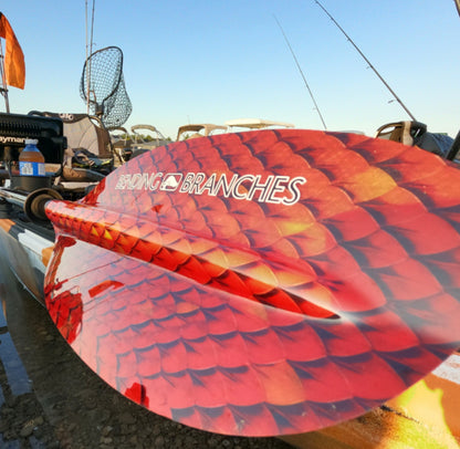 Red kayak with 'Branches' branding on a boat ramp